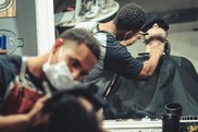 Men in barbershop wearing face coverings