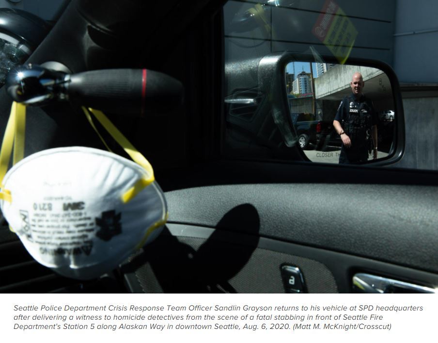 SPD Officer approaches his vehicle and is reflected in vehicle's side-view mirror.