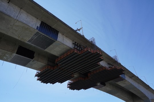 Crews move work platforms along the bottom of the bridge, installing the carbon fiber wrap – the black bands – as they go.