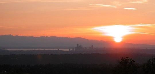 Photo of the Seattle Skyline covered in smoke against an orange sunset