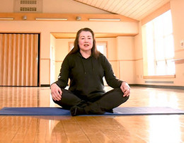 Woman seated cross legged on yoga mat