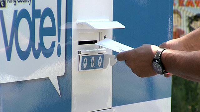 A voter puts their ballot into a ballot box