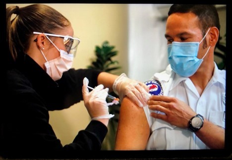 Nurse administers COVID-19 vaccine to paramedic Alan Goto 