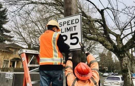 Installing a speed limit sign.