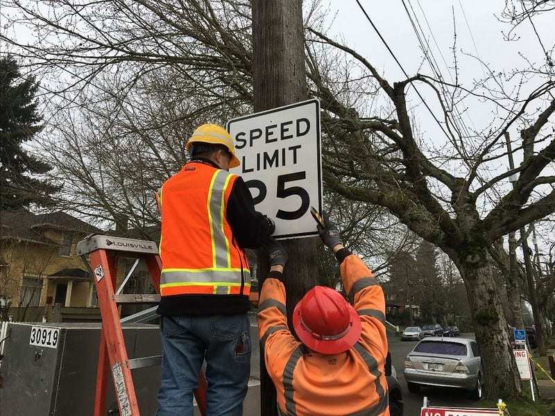 Seattle Department of Transportation crew members install a 25 mile per hour sign