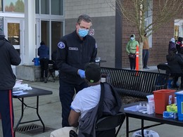 Seattle Fire paramedic vaccinates a home health care worker at a pop-up vaccination clinic