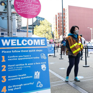 A volunteer welcomes guests at the entrance of the community vaccination clinic at Lumen Field in Seattle 