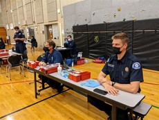 Fire Department Sitting at School-Based Vaccination Clinic Table 