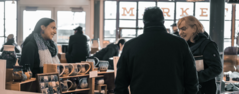 A small business owner at Pike Place market interacting with two customers