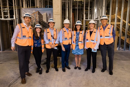 Mayor Durkan and others pose while wearing orange safety vests and hardhats during construction at affordable housing project.