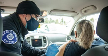 Image of Seattle Fire Department staff vaccinating an individual in her car