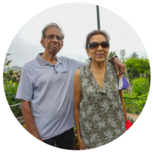 A couple stands in their community garden, smiling.