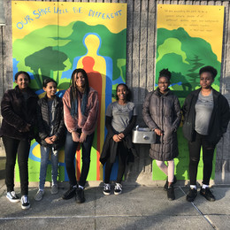 A group of teenage girls standing in front of a mural in a park