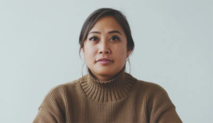 Headshot of a Filipino woman wearing a brown turtleneck sweater with a gray background