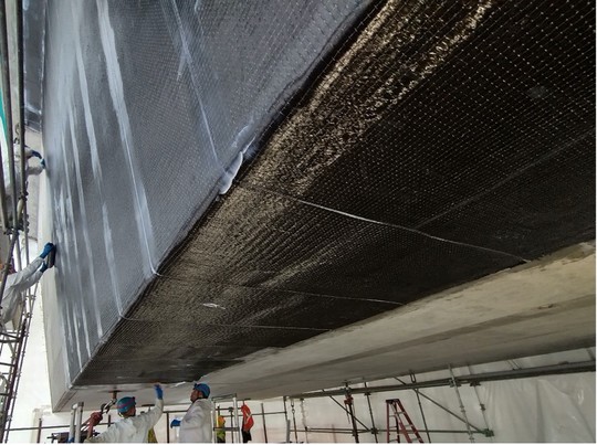 Applying sheets of carbon-fiber to sections of the bridge’s girders that have been injected with epoxy. 