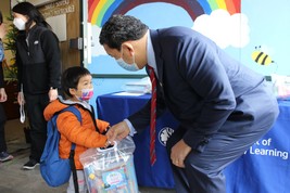 Mayor Harrell hands learning supplies to a Seattle pre-school program student