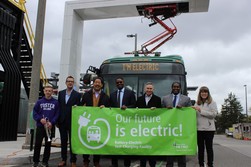 Mayor Harrell stands in front of new electric bus with local leaders holding a "Our future is electric!" banner.