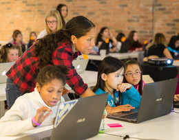 Woman helps children on laptops