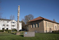 The exterior of a brick building with a Seattle Public Library sign and large telephone pole with carvings up the side