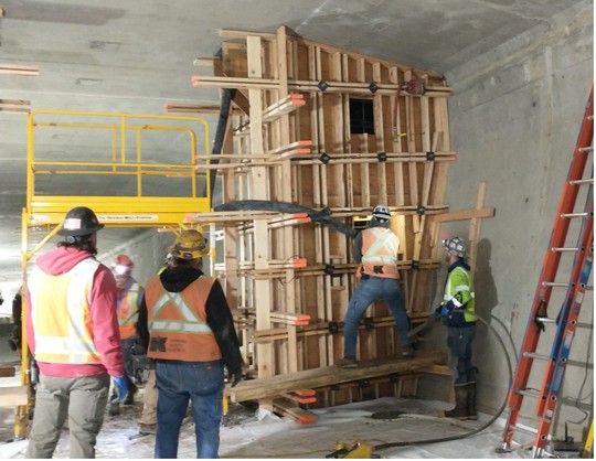Crews feed the concrete pump hose into the form for the post-tensioning system. 