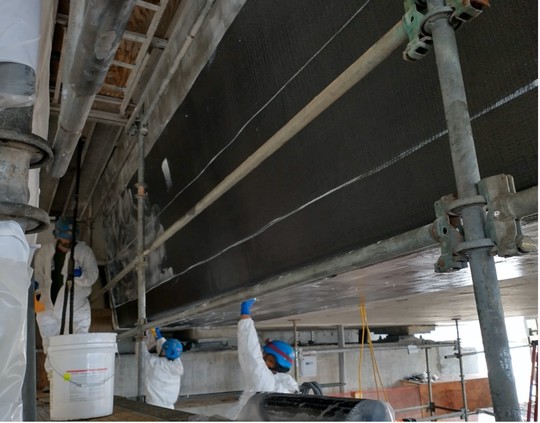 Applying carbon-fiber sheets to the underside of the bridge to strengthen the concrete. 