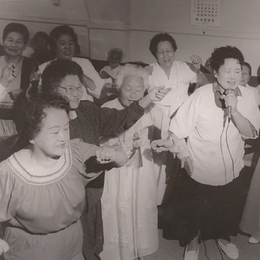 A black and white vintage photo of a group of Asian women singing and dancing