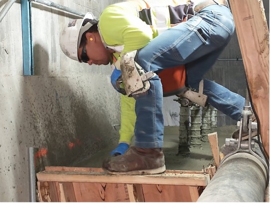 A crew member smooths the surface of a newly poured concrete anchor.  