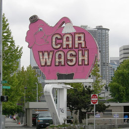 A large neon sign featuring a happy pink elephant that says "Car Wash"