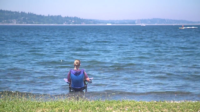 A woman sits on a lawn chair in in the lake