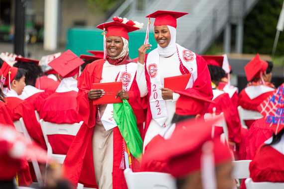Two Cleveland High School graduates smile as they exit the commencement stage with diplomas in hand.