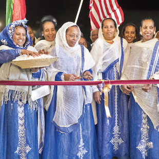 A group of people wearing cultural robes and scarfs, smiling