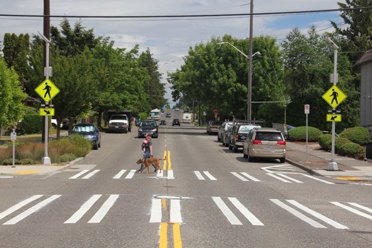 A woman crosses the street at 17th Ave SW and SW Henderson St.