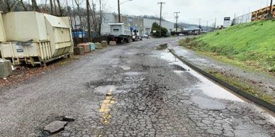 Before on Occidental Ave S between S Kenyon St & S Sullivan St, showing damaged pavement