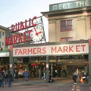 Red neon sign that says "Public Market" with an analogue clock at the entrance of Pike Place Market