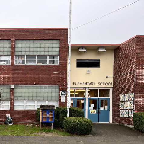 The exterior of a brick elementary school with words above the door reading "Alki Elementary School"