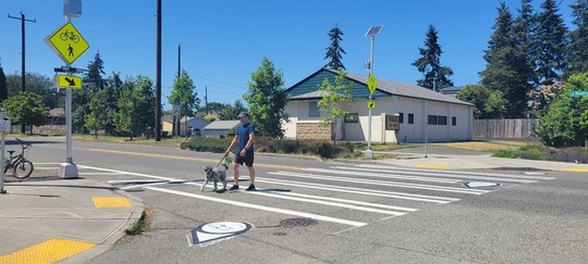 A West Seattle community member crosses SW Henderson St at 17th Ave SW where we installed a pedestrian crosswalk sign.