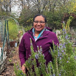 A Black woman stands, smiling in a P-Patch community garden