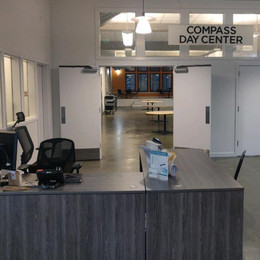The front desk of an emergency overnight shelter with a sign hanging that reads "Compass Day Center"