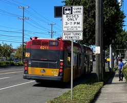 Photo of the back of a bus that is on the side of the street next to a sign that indicates bus only hours