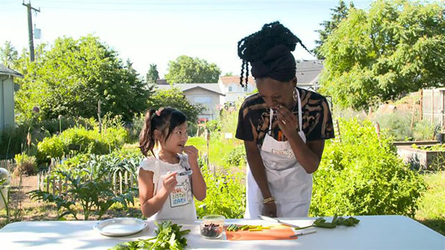 A woman and young girl stand at a table and eat celery on a farm