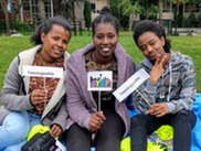 Three Black teenage girls smile for the camera and hold signs promoting SYEP and #unstoppable at the 2019 Capstone event