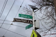 A sign pole with a green street sign that says "E Union St." and a brown street sign that says "D'Vonne Pickett Jr. Way"