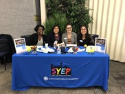 SYEP staff sitting at an information table with a SYEP banner waiting to answer questions and work with you