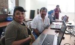 Latino woman and man in a classroom sitting at computers