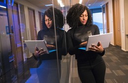 photo of mirror image of black woman leaving again glass wall