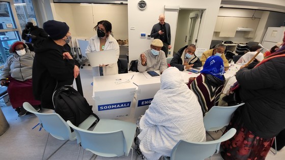 Community members sit across a table with language interpreters in a community room