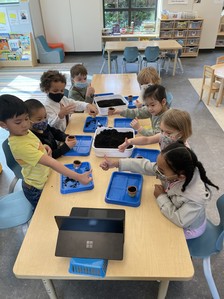 A group of young children gathered around a table at Refugee Women's Alliance child care room