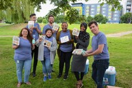 Summer Food Service Program team poses for the camera holding up box lunches available for children at the Othello Park kickoff event