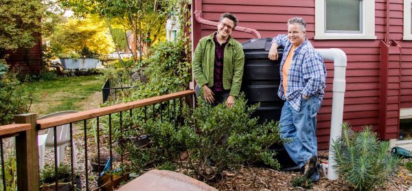 Two people standing in a garden outside their home highlighting their new RainWise cistern.