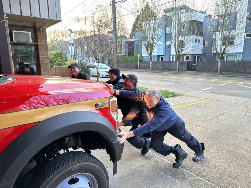 Firefighters push the new Air 26 apparatus into the station garage